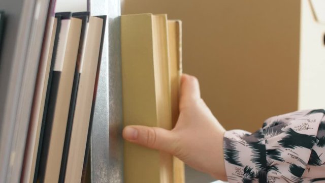 Close up of woman hand puts book on shelf. 4k slow motion footage. 4k.