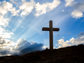 Silhouettes of crucifix symbol with bright sunbeam on the colorful sky background
