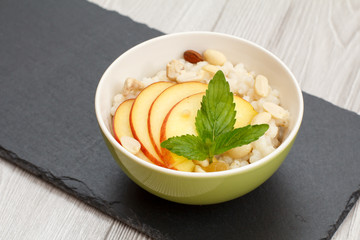 Sorghum salad with nuts and fresh peach on black stone board.