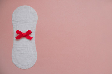 Sanitary pad with a red bow on a pink background. Copy space