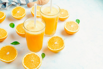 Orange juice and orange fruits with green leaves on white background.
