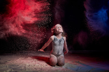 Small girl during photoshoot with flour in dark studio