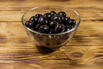 Pickled black olives in glass bowl on wooden table