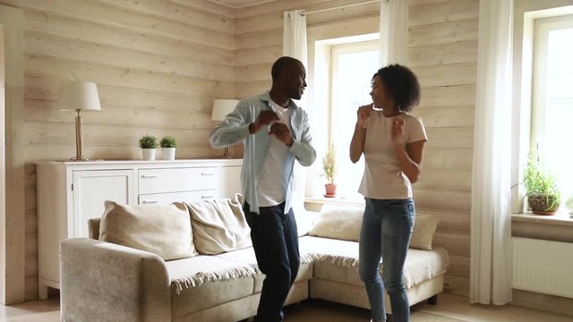 African couple having fun dancing on date in living room