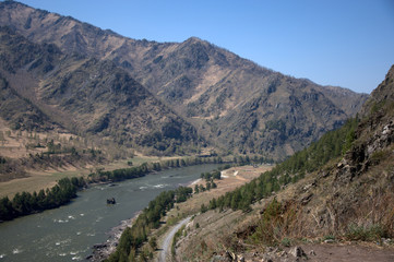 The swift turquoise river flows through the valley in the fusion of mountain ranges.