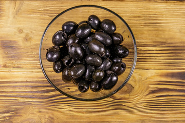 Pickled black olives in glass bowl on wooden table