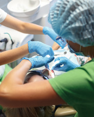 Dentist and nurse doing surgery on a young patient in a dental office