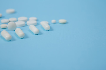 Fototapeta na wymiar White medical pills on blue background.