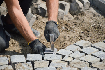 worker stacks paving stones