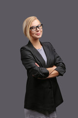 Woman, a teacher in a jacket and glasses on a gray background, expresses emotions. Copy space.