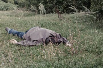 The corpse of a tramp in the grass. Criminal. Alcoholic intoxication. Killing a homeless man. dead body after lightning strike