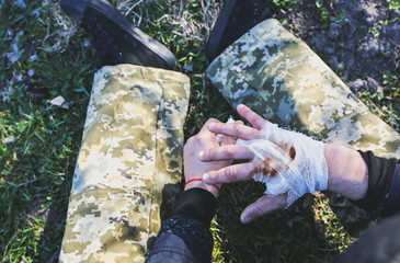 Man is putting bandage on bleeding wound. Injured hand. Cut with a knife. Tourist in the nature....