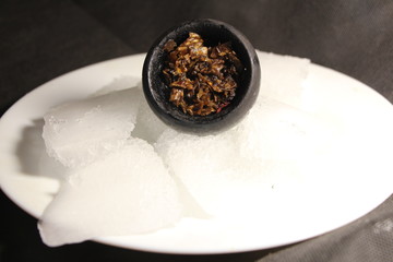 bowl with tobacco for hookah. berries on a black background