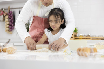 Happy Asian family Father and Daughter are rolling pin thresh flour for making bakery in the kitchen in home. family cooking food Concept.