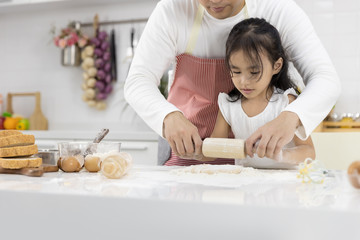 Happy Asian family Father and Daughter are rolling pin thresh flour for making bakery in the kitchen in home. family cooking food Concept.