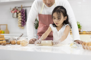 Happy Asian family Father and Daughter are rolling pin thresh flour for making bakery in the kitchen in home. family cooking food Concept.