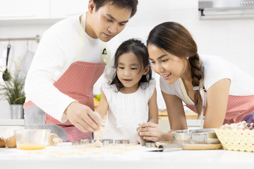 Obraz na płótnie Canvas Happy Asian family Father, Mother and Daughter are preparing the dough, bake cookies in the kitchen in home. family cooking food Concept.