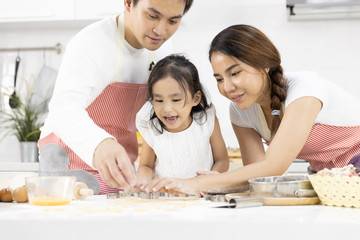 Happy Asian family Father, Mother and Daughter are preparing the dough, bake cookies in the kitchen in home. family cooking food Concept.