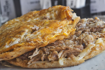 Traditional Serbian meat breakfast - fresh bun, lepinja, stuffed with scrumbled egg, chopped onion, kajmak cheese and pork under sach (sac)