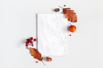 Autumn composition. Paper blank, flowers, leaves on gray background. Autumn, fall, thanksgiving day concept. Flat lay, top view, copy space