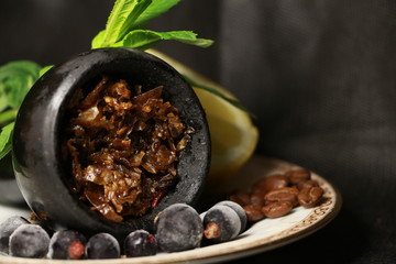 bowl with tobacco for hookah. berries on a black background