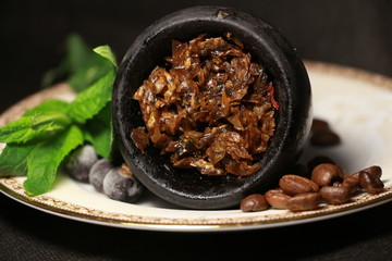 bowl with tobacco for hookah. berries on a black background