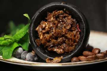 bowl with tobacco for hookah. berries on a black background