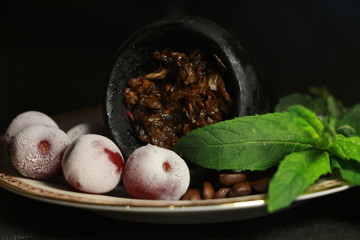 bowl with tobacco for hookah. berries on a black background