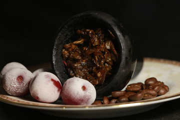 bowl with tobacco for hookah. fruits and berries on a black background. smoke hookah