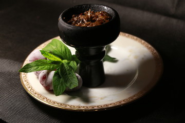 bowl with tobacco for hookah. fruits and berries on a black background. smoke hookah