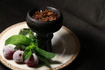 bowl with tobacco for hookah. fruits on a black background