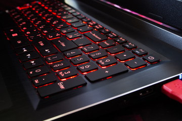 Red backlit laptop keyboard. Close-up.