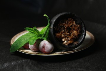bowl with tobacco for hookah. berries on a black background