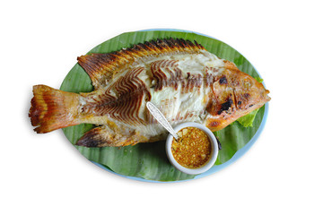 Fish burned, cooked and placed on banana leaves with Sour sauce, sour spicy and minced garlic. isolated on white background. This has clipping path.             
