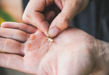 Man is putting maggot on fish-hook. Fishing outdoors. Hobby in the nature.