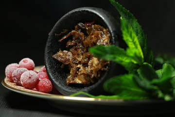 bowl with tobacco for hookah. berries on a black background