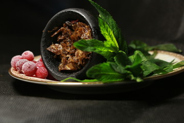 bowl with tobacco for hookah. fruits and berries on a black background. smoke hookah