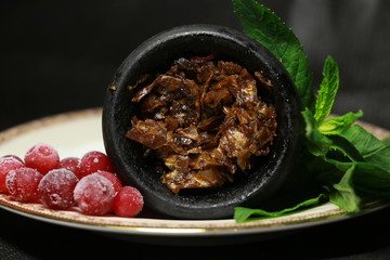 bowl with tobacco for hookah. berries on a black background