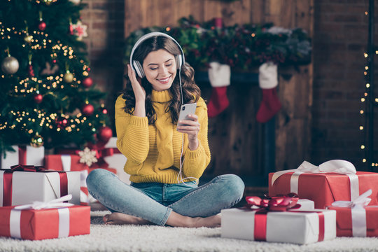 Full length body size photo of charming cute nice girl wearing yellow jumper denim knitted toothily smiling watching something on phone while listening to audio