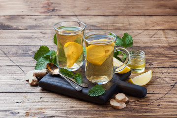 Two cups of natural herbal tea ginger lemon mint and honey on a wooden background. Copy space