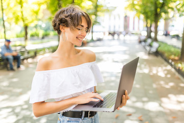 Young woman using laptop outside in the park