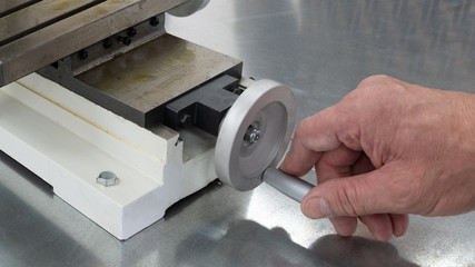 Part of a milling or drilling machine. The male hand holds the handle of the longitudinal or...