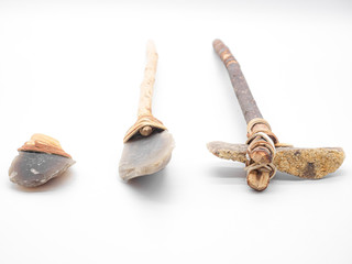 Replicas of the primal stone tools with wooden handles and leather strapping isolated on white background. Primitive stone axe, dagger and hammer: weapons of the prehistoric peoples.Selected focus.