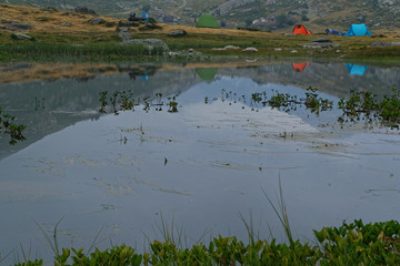 Tentes reflects on a quite mountain lake of french alps at dawn