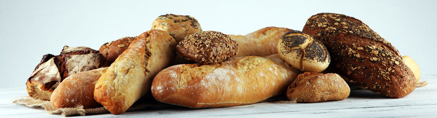 Assortment of baked bread and bread rolls on white table background