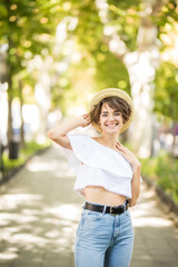 Closeup portrait of a young woman in a straw hat. Laughing girl enjoying her time outside in park