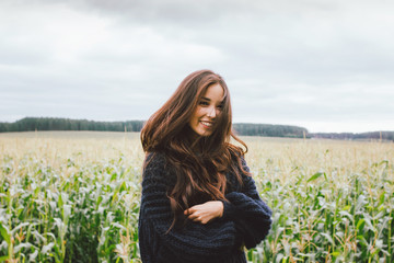 Beautiful carefree long hair asian girl in knitted sweater in autumn corn field. Sensitivity to nature concept