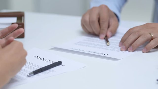 Couple signing divorce policy, woman taking off engagement ring from finger