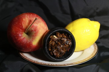 bowl with tobacco for hookah. berries on a black background