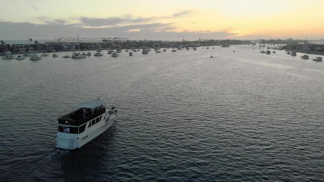 Yacht overhead perspective, sailing in marina at sunset golden hour. Newport Bay in Newport Beach, Orange County, California. Closing scene.